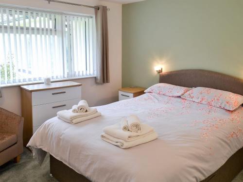 een slaapkamer met een bed met handdoeken erop bij Bluebell in Saint Ewe