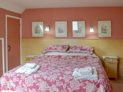 a bedroom with a pink bed with towels on it at Cherry Tree Cottage in Bovey Tracey