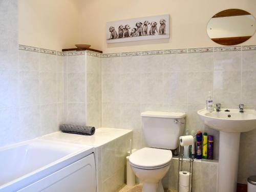 een badkamer met een toilet, een wastafel en een bad bij The Dairy - 17321 in Compton