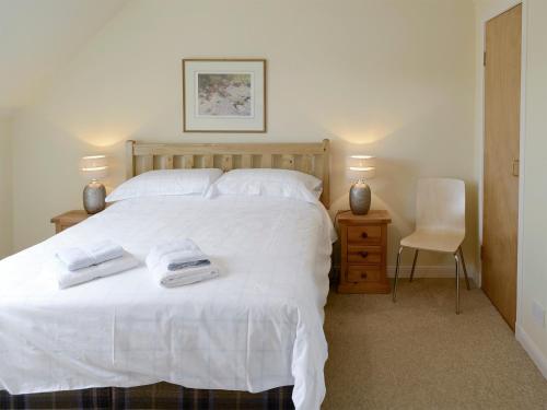 a bedroom with a white bed with two towels on it at Birch Cottage in Glenrossal