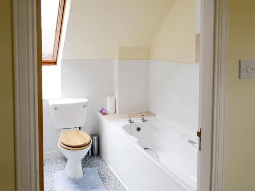 a bathroom with a toilet and a bath tub at Birch Cottage in Glenrossal