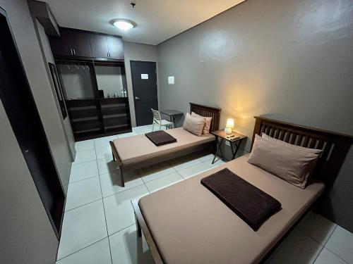 Habitación con 2 camas y una silla. en Inn De Avenida, Makati, en Manila