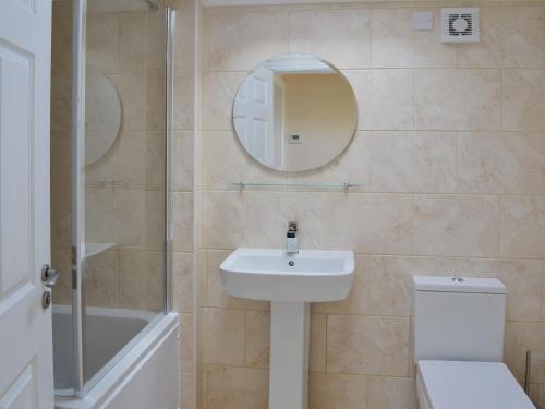 a bathroom with a sink and a toilet and a mirror at Oak Cottage in Winthorpe