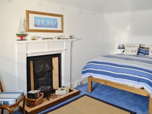 a bedroom with a bed and a fireplace at Boatmans Cottage - 27787 in Portessie