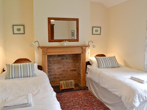 two beds in a room with a fireplace and a mirror at Rhydlanfair in Capel Garmon