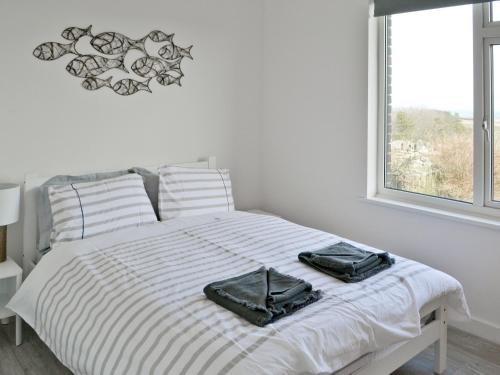 a white bedroom with a bed with two bags on it at Eider Cottage in Embleton