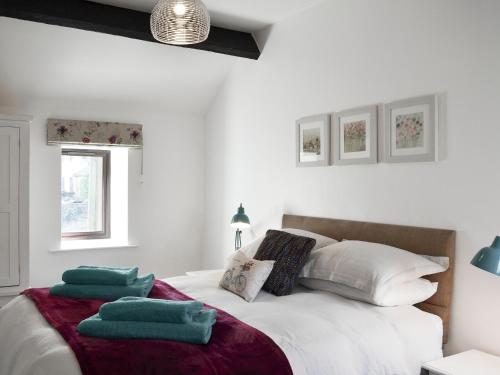 a white bedroom with a bed with green towels on it at Bellhouse Croft in Shelley