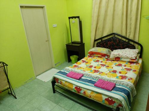 Schlafzimmer mit einem Bett mit bunter Bettwäsche und Kissen in der Unterkunft HOMESTAY JANNATI TAMBUN in Tambun