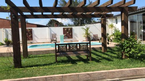 een houten pergola met een bankje naast een zwembad bij Quitinete com piscina em Balneário Pinhal in Pinhal