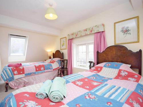 1 dormitorio con 2 camas y ventana en Pepper Pot Cottage, en Compton