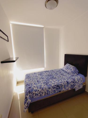 a bedroom with a bed with a blue comforter at Acogedor Departamento 3 Hab Piura in Piura