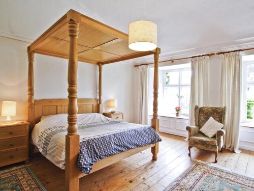um quarto com uma cama de dossel e uma cadeira em Manor House em Uny Lelant