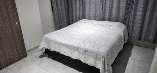 a bed with a white blanket on it in a bedroom at Hermoso apartamento iluminado cerca al Metropolita in Barranquilla