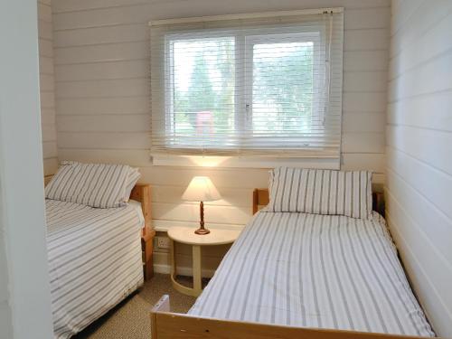 2 camas en una habitación con mesa y ventana en Roscarrock, en Bradworthy