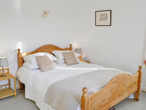 a bedroom with a large bed with white sheets and pillows at Low Mill Cottage in Grassington