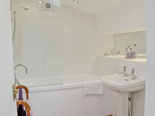 a white bathroom with a sink and a shower at Low Mill Cottage in Grassington