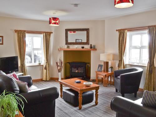 uma sala de estar com sofás e uma mesa em Alices Cottage em Lanehead