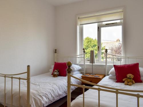 2 camas individuais num quarto com uma janela em Shingle Cottage em Whitstable