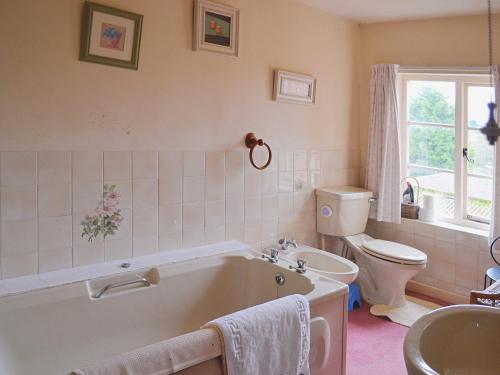 een badkamer met een bad, een toilet en een wastafel bij The Farmhouse in Newent
