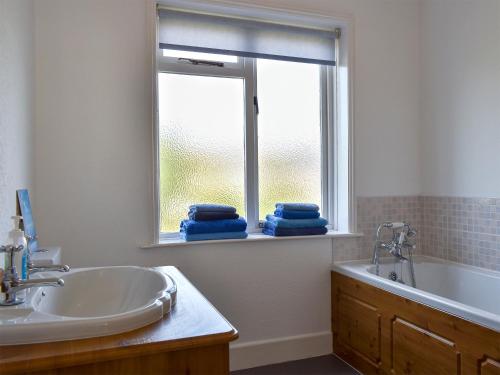 uma casa de banho com um lavatório, uma banheira e uma janela em Shingle Cottage em Whitstable