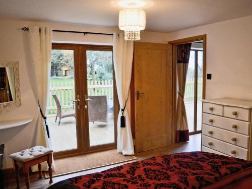 Ampney CrucisにあるDove Cottageのベッドルーム1室(ベッド1台付)、スライド式ガラスドアが備わります。