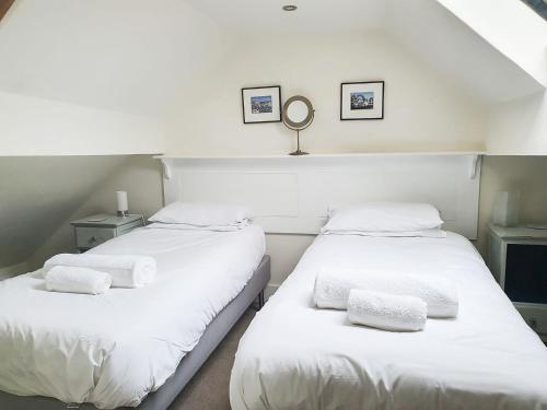 two beds in a room with white sheets and towels at Madeleines Barn in Wells next the Sea