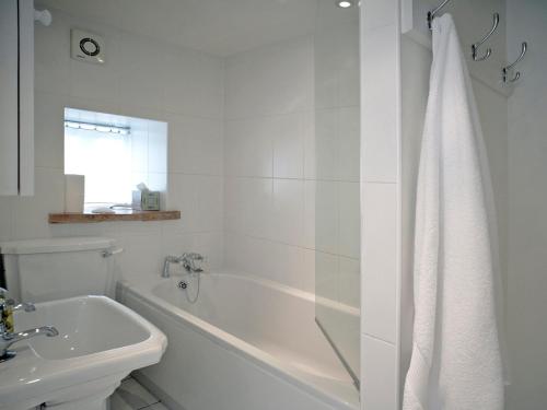 uma casa de banho branca com uma banheira e um lavatório em Madeleines Barn em Wells-next-the-Sea