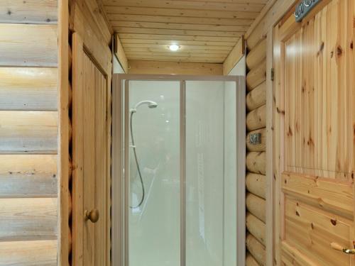 a glass shower door in a room with wooden walls at Fingask Log Cabin - S4394 in Glenfarg