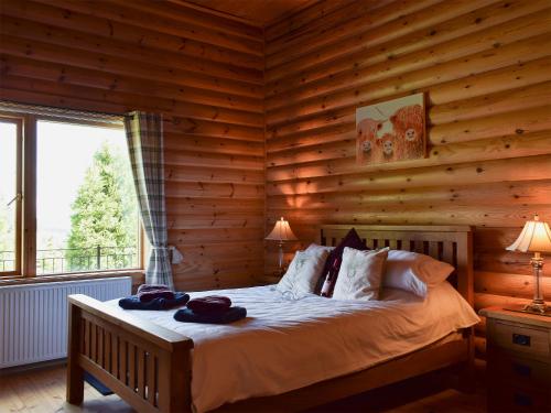 um quarto com uma cama num chalé de madeira em Fingask Log Cabin - S4394 em Glenfarg