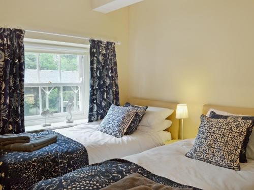 a bedroom with two beds and a window with curtains at Stable Cottage 1 in Rudston
