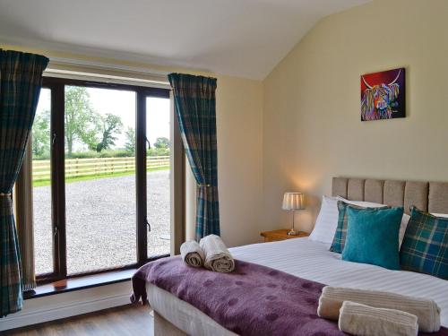1 dormitorio con cama y ventana grande en Brunos Bothy en Wigton