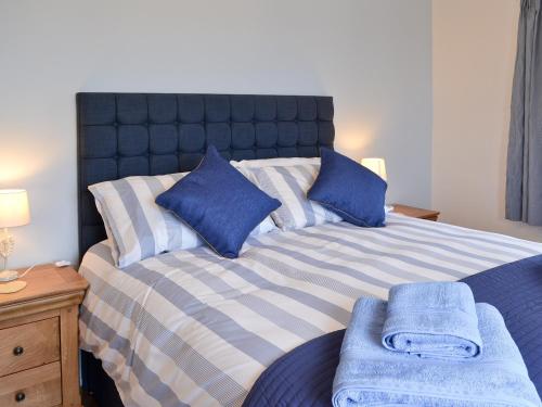 een slaapkamer met een bed met blauwe en witte kussens bij Bwthyn Pereos in Llanrhwydrys
