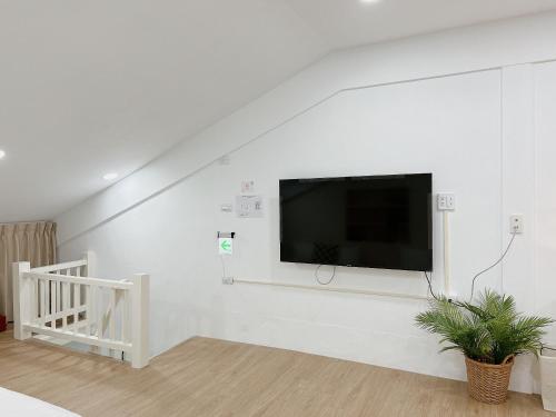Soda White Tainan Homestay في تاى نان: غرفة معيشة مع تلفزيون بشاشة مسطحة على جدار أبيض