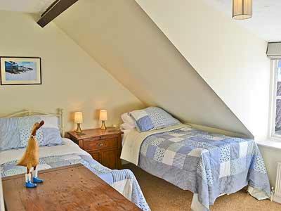 a attic bedroom with two beds and a doll on a table at Clipper Cottage in Wells next the Sea