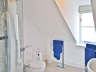 a bathroom with a toilet and a glass shower at Clipper Cottage in Wells next the Sea
