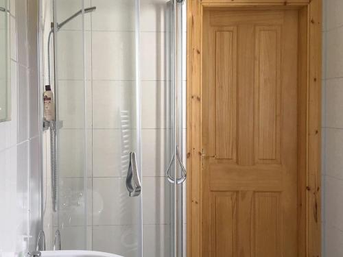 a bathroom with a shower with a door and a sink at Taigh an Tuath in Isleornsay