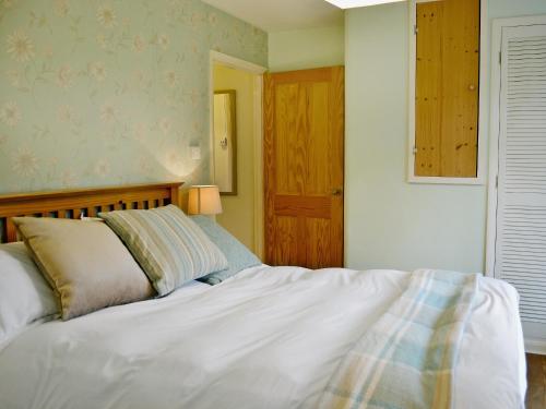 een slaapkamer met een wit bed en een houten hoofdeinde bij Palm Leas - E3587 in Ilfracombe