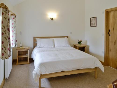 een slaapkamer met een groot wit bed en 2 tafels bij Herons Weir in Buckland Dinham