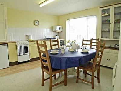 a kitchen with a table and chairs with a blue table cloth at Brightlands Apartment in Poughill