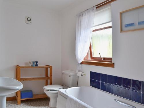 baño con bañera, aseo y ventana en Bethany Cottage, en Aberfoyle