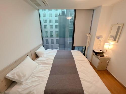 a large bed in a room with a large window at K9 Myeongdong Hotel in Seoul