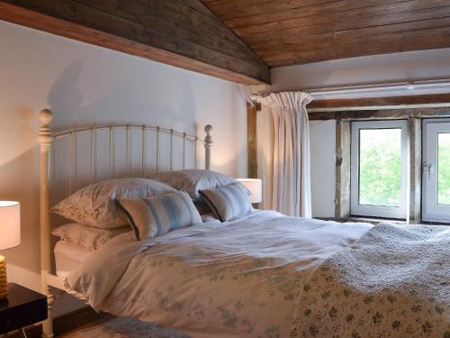 1 dormitorio con 1 cama grande y 2 ventanas en Pear Tree House Annexe, en Holmfirth