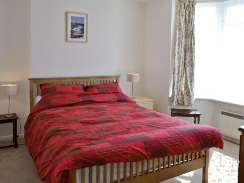 a bedroom with a bed with a red comforter and a window at Ferrybridge View in Wyke Regis