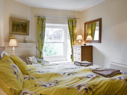 a bedroom with a bed with yellow sheets and a window at Dove Cottage in Middleham