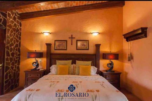 ein Schlafzimmer mit einem Bett mit einem Kreuz an der Wand in der Unterkunft Quinta El Rosario maravilloso lugar in Lagos de Moreno