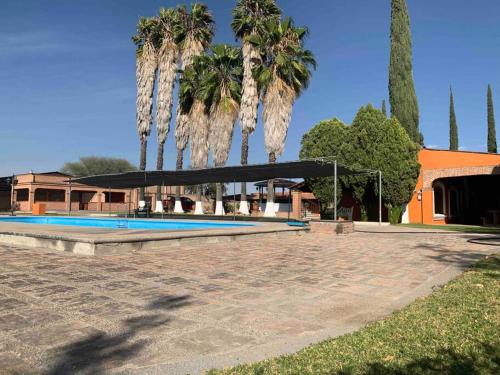 einen Pool mit einem Pavillon und Palmen in der Unterkunft Quinta El Rosario maravilloso lugar in Lagos de Moreno