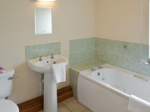 a bathroom with a sink and a tub and a toilet at The Coach House in Somersal Herbert