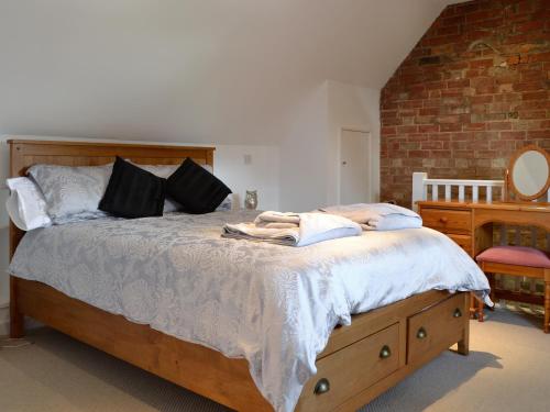 a bedroom with a large bed with a brick wall at The Lodge At The Granary in Alderton