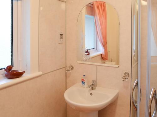 a white bathroom with a sink and a mirror at Horsemans in John O Groats