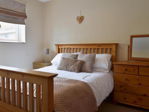 a bedroom with a bed and a dresser with a mirror at Poplar Cottage in Cote